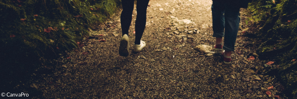 zwei Menschen gehen gemeinsam einen Waldweg entlang