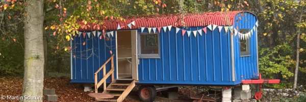 ein geschmückter, blauer Bauwagen im Herbst