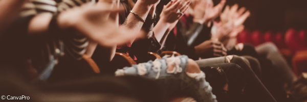 Menschen sitzen in einem Theatersaal und klatschen