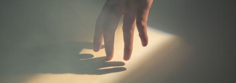 eine Hand berührt ihren eigenen Schatten