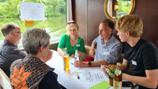 5 Menschen sitzen um einen Tisch und diskutieren