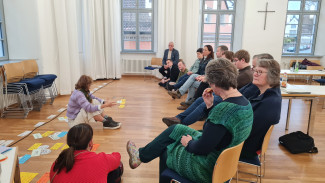 Mitglieder des Dekanatsausschusses sitzen um einen Zeitstrahl, der am Boden ausgelegt ist