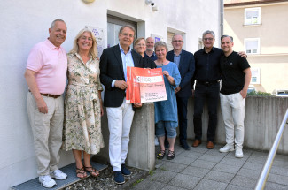 Vertreter der Rotarier und des Diakonischen Werkes stehen auf der Treppe mit dem Übergabescheck