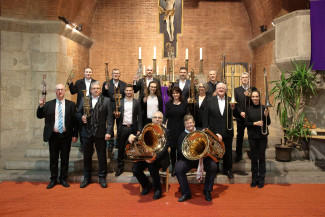 viele Mitglieder eines Blasmusikensembles mit ihren Instrumenten