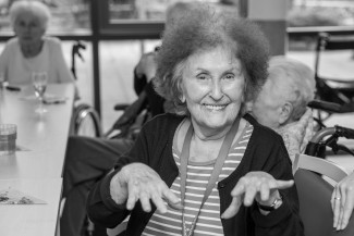 Eine alte Frau lacht und spielt Klavier in der Luft