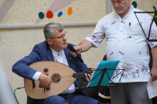 Zwei Männer, einer davon spielt auf der Saz, er ist der Imam der Dibtib Moschee