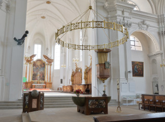 Der Altarraum von St. Stephan - lichtdurchflutet, ein Tischaltar, ein großer runder hängender Kerzenleuchter in gold