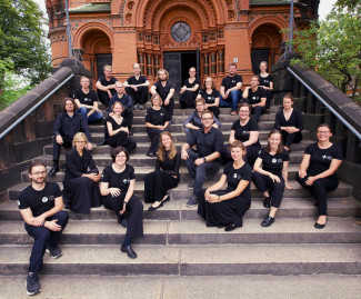 viele junge Menschen in schwarzen T-Shirts sitzen auf Stufen, die zu einer Kirche führen