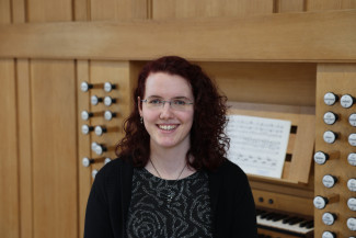 Nadja Rangott, eine Frau mit dunklen Haaren, Brille und schwarzem Oberteil vor einer Orgel