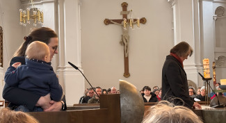 Zwei Frauen sprechen in der Kirche, eine hält ihr Kleinkind auf dem Arm
