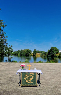Ein Altar im Grünen, im Hintergrund ein Fluss und Bäume