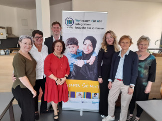 7 Menschen stehen um den Banner von WoFa