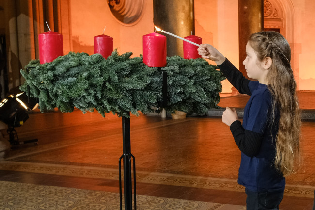 Kind zündet Kerze an Adventskranz an