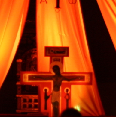 Taize-Kreuz in orangenes Licht getaucht