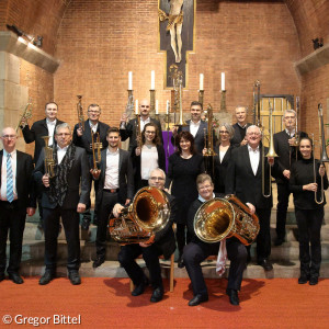 viele Mitglieder eines Blasmusikensembles mit ihren Instrumenten