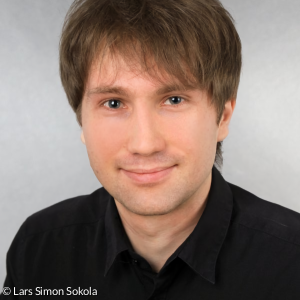 Lars Simon Sokola, ein Mann mit braunen Haaren und schwarzem Oberteil